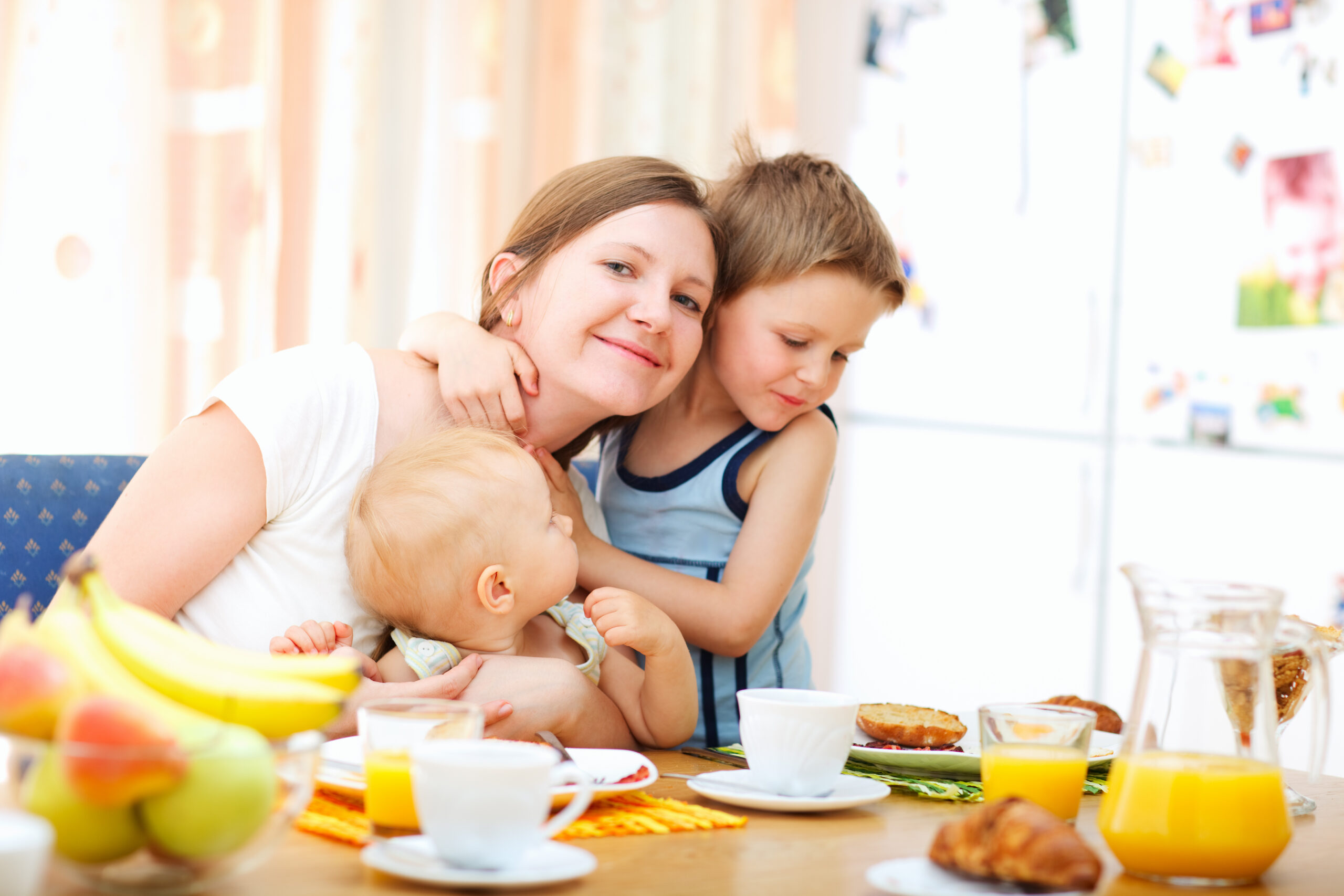 Young happy mother and two kids having breakfast together